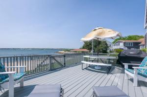 eine Terrasse mit Stühlen, einem Sonnenschirm und einem Grill in der Unterkunft 5 Bryant Road Bourne Sunset Cottage in Buzzards Bay
