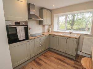een keuken met witte kasten, een wastafel en een raam bij The Hollow in Hexham