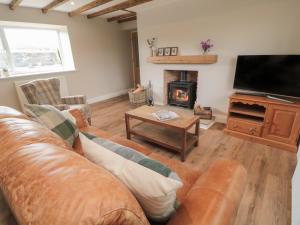 a living room with a leather couch and a fireplace at The Hollow in Hexham