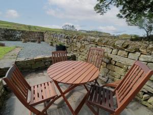 a wooden table and two chairs and a stone wall at The Hollow in Hexham