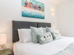 a bedroom with a white bed with a painting on the wall at Strawberry Bank - Kingfisher in Holsworthy