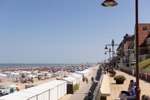 een strand met parasols en mensen die op een stoep zitten bij Leader De Haan - Casselbergh Residences in De Haan