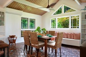 a dining room with a table and chairs and windows at Kaiana Villa in Princeville +18 photos