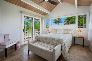a bedroom with a bed and a chair and windows at Kaiana Villa in Princeville
