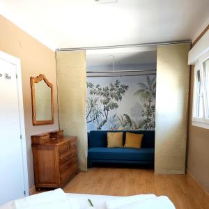 a living room with a blue couch and a mirror at Las Tres Mimosas in San Vicente de la Barquera