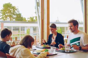 a group of people sitting around a table eating food at Varala Sports & Nature Hotel in Tampere