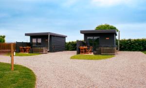 two black cabins with tables and chairs in a yard at Saul Lodges 