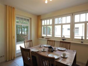 a dining room with a table with chairs and windows at Kinnekulle 2 in Zingst