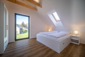 1 dormitorio con cama blanca y ventana grande en Holiday House U Hájenky 11P Lipno Home, en Lipno nad Vltavou
