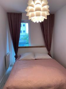 - une chambre avec un lit, un lustre et une fenêtre dans l'établissement Apartament Rose 9 Świnoujście, à Świnoujście