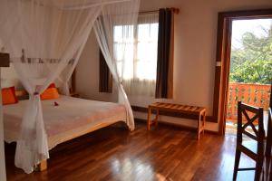 ein Schlafzimmer mit einem Bett und einem großen Fenster in der Unterkunft Hotel Ambalakely in Ambalakely