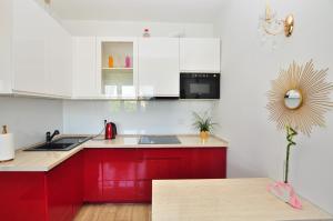 - une cuisine rouge avec des placards blancs et un évier rouge dans l'établissement Apartament Chełmiński, à Toruń