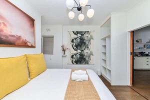 a white room with a large bed and a painting at Cosy 1BD APT in the Mother City in Cape Town
