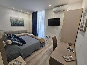 - une chambre avec un lit, une télévision et une table dans l'établissement City Rooms Katane, à Catane