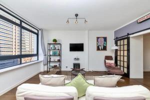 a living room with two white couches and a tv at Cosy 1BD APT in the Mother City in Cape Town