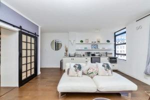 a living room with a white couch and a kitchen at Cosy 1BD APT in the Mother City in Cape Town