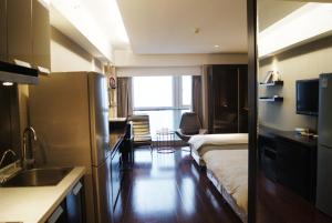 a room with a bed and a kitchen with a sink at Kaibin Apartment- Nanjing University Branch in Nanjing