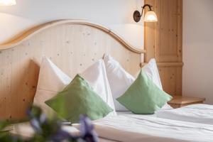 ein Bett mit weißen und grünen Kissen darauf in der Unterkunft Residence Diana Apartment 103 in Terenten