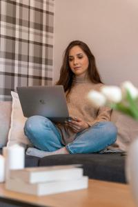 kobieta siedząca na kanapie z laptopem w obiekcie Apartamenty Pod Gondolą - Mountain Resort Villa - Dream Apart w Szczyrku