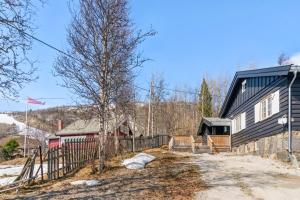 a black house with a fence next to a building at Solsiden - in the center of Geilo in Geilo
