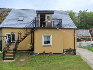 a yellow house with a staircase and a balcony at Wczasy u Jasia in Trzęsacz