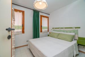 Rena Bianca House by Wonderful Italy في أولبيا: غرفة نوم بسرير ابيض وستائر خضراء