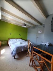 1 dormitorio con cama y pared verde en Hôtel Ecu de france, en Secondigny