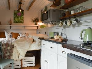 a kitchen with a bed in the middle of it at Spruce Shepherds Hut in Wilmslow