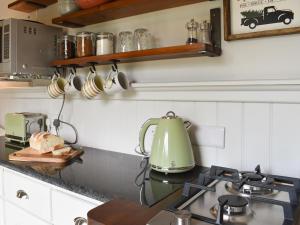 a kitchen with a green tea kettle on a stove at Spruce Shepherds Hut in Wilmslow