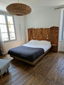 1 Schlafzimmer mit einem Bett, Holzboden und 2 Fenstern in der Unterkunft Au Pont Vieux 9 personnes in Espalion