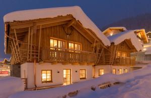 a log home in the snow at night at FIRSTpeak Appartements und Chalets in Zauchensee