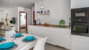a kitchen with white cabinets and a table with blue plates at Loft near Carvajal beach by Costarentals - Ref 16 in Torremuelle +25 photos
