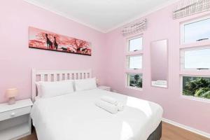 a bedroom with a white bed and two windows at Colourful & cheery Devils' Peak Views 3BD home in Cape Town
