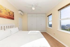 a white bedroom with a bed and a window at Colourful & cheery Devils' Peak Views 3BD home in Cape Town
