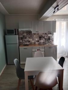 Le Soler的住宿－maison cosy，一间厨房,里面配有白色的桌子和椅子
