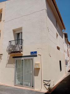 a white building with a balcony and a window at maison cosy in Le Soler