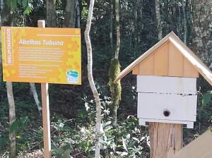 um sinal ao lado de uma casa de pássaros numa floresta em Ózera Hotel Fazenda em Prudentópolis