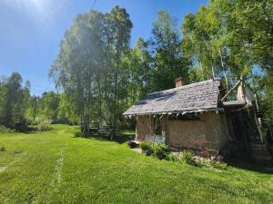 una vieja casa de piedra en un campo de hierba en Baltās Raganiņas pirts en Sabile