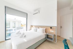 a bedroom with a white bed with a large window at Thalassa & Thalassa Prive Residential Complex in Ofrínion +55 photos