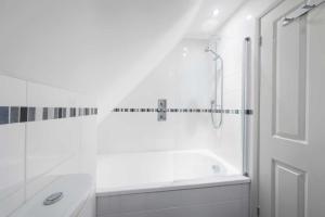 a white bathroom with a tub and a shower at Upper Seaton in Salcombe