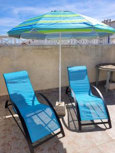 2 sillas azules y una sombrilla en el patio en Casa Danas en Torrevieja