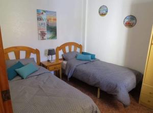 a bedroom with two beds and a table with a lamp at Casa Danas in Torrevieja