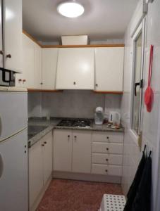 cocina pequeña con armarios blancos y fogones en Casa Danas en Torrevieja