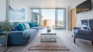 a living room with a blue couch and a table at Treetops in Salcombe