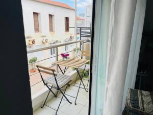 balcone con tavolo e sedie. di Cozy Nest - 2min To Beach, 6min Walk To Old Town a Chania