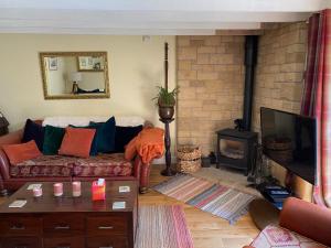 a living room with a couch and a fireplace at Wisteria Cottage in Alnham