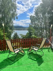 two chairs on a lawn with a fence and a lake at Zajazd Cicha Woda in Maniowy