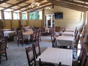 an empty dining room with tables and chairs and a television at Status Hotel in Poltava