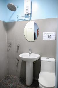 ein Badezimmer mit einem Waschbecken, einem WC und einem Spiegel in der Unterkunft Sea Apartment-Pinca in Manila