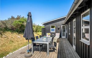 eine Terrasse mit einem Sonnenschirm und einem Tisch auf einer Terrasse in der Unterkunft Cozy Home In Lkken With Kitchen in Løkken